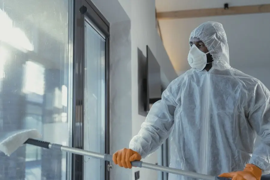 A technician in a white suit mopping a bright room.